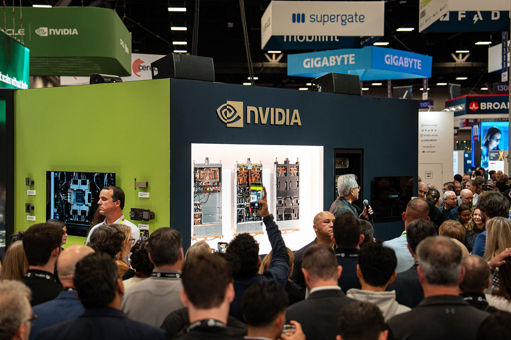NVIDIA Founder Jensen Huang gives a speech in front of the NVIDIA booth as a crowd looks on.