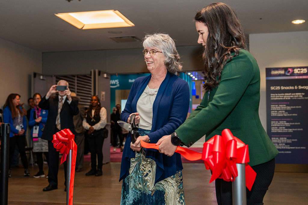 Staff and event goers look on as Lori Diachin, general chair of SC25, cuts the ceremonial ribbon to officially open the conference.